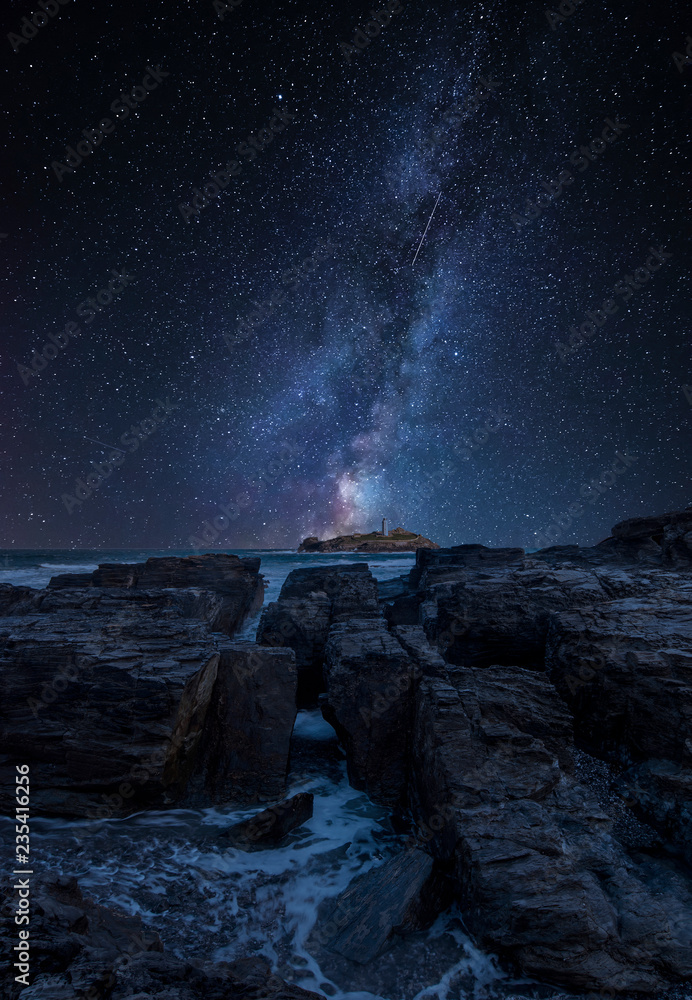 Vibrant Milky Way composite image over landscape of Godrevy lighthouse on Cornwall coastline in England