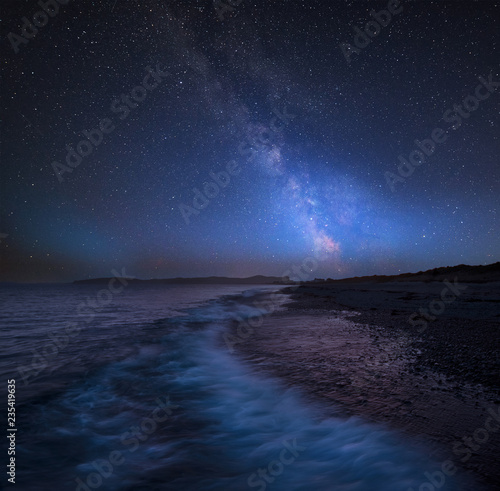 Vibrant Milky Way composite image over landscape of West coast of Wales