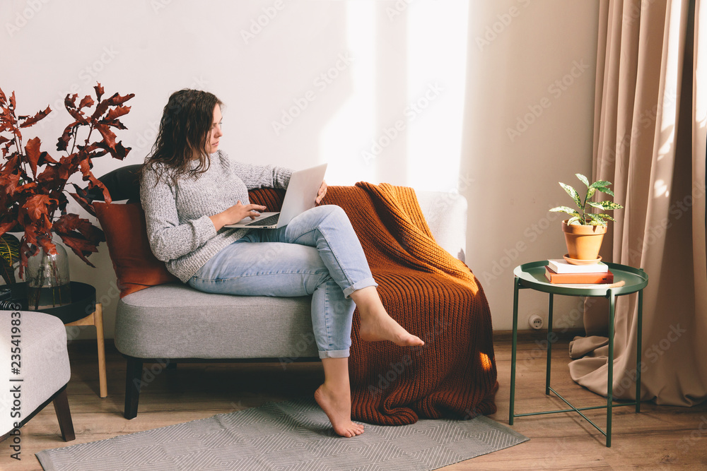 Young woman working on the notebook. Girl lying on the sofa. Woman holding laptop in hands Young woman working on the notebook. Girl lying on the sofa. Woman holding laptop in hands