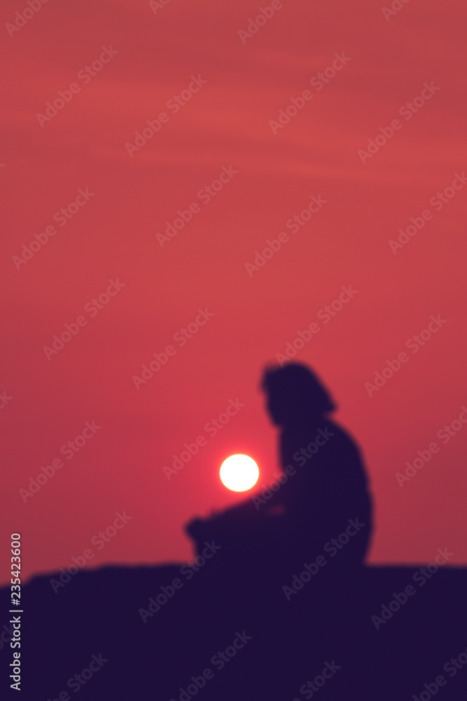 Elderly woman sitting alone and looking at the sunset.