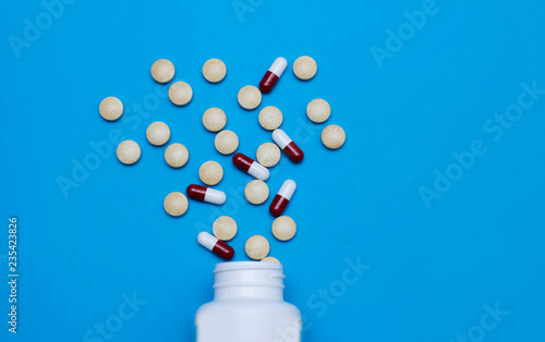 Medical tablets, pills scattered over a blue background