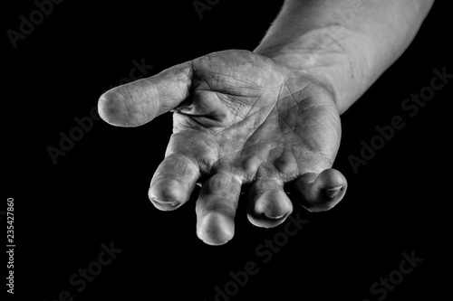 Helping Hands concept. Hand of a man palm up reaching, giving, asking or holding isolated on black background.