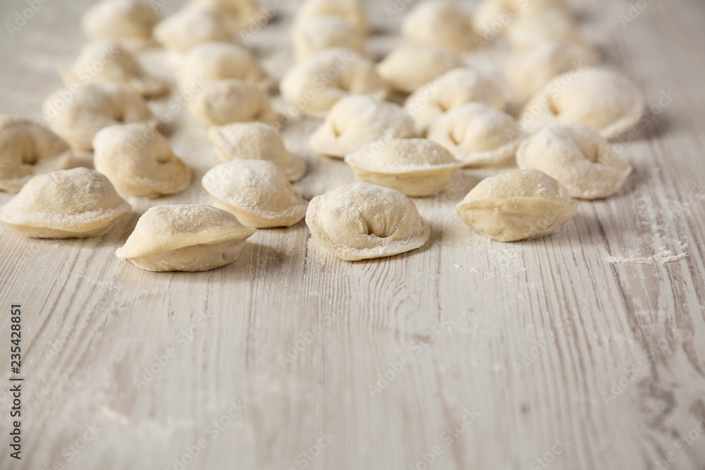 Homemade raw tortellini on white wooden background, side view. Copy space. Homemade raw tortellini on white wooden background, side view. Copy space.