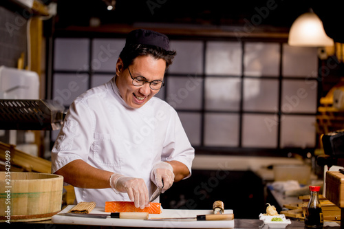 smiling Asian man is sliecing roll in the cafe. healthy food concept. tasty tradition . close up photo.copy space photo