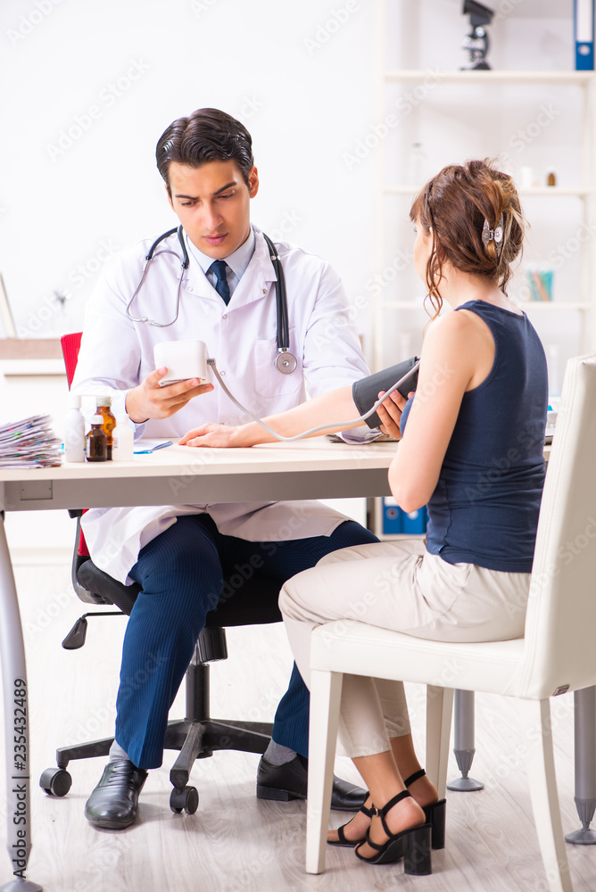 Young doctor checking woman's blood pressure Young doctor checking woman's blood pressure