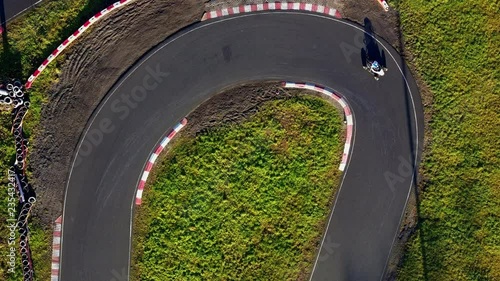 Aerial view; drone flight over buggy kart racing track; curved, winding and turning asphalt road; competition between participants drivers, fans behind; active healthy lifestyle concept; leisure time