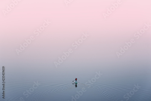 Obraz na płótnie SUP Surfing,View From Above: Lonely Man Is Training On Sup Board On A Large Lake During Pinky Sunset. Surfer.Man In Red Jacket Stand On Sup Paddle Board, Exercising On The Alpine Lake In Mongolia w salonie