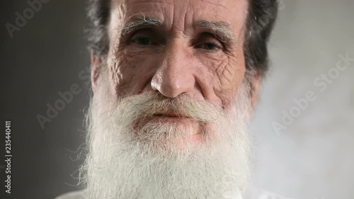 Smiling and handsome elderly man with white beard posing for the camera, closeup portrait photo