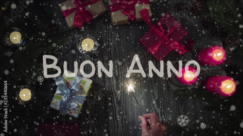 Greeting card Buon Anno, Happy New Year in italian language, falling snow, candles and gifts