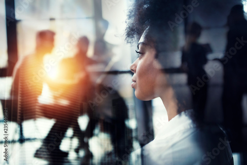 Businesswoman at the office looks through the window for the future. double exposure
