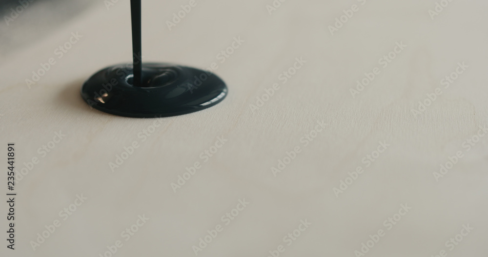 closeup pouring black paint on plywood closeup pouring black paint on plywood