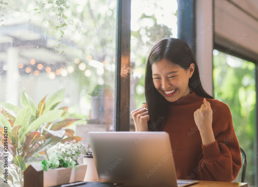Young Asian woman celebrate success or happy pose with laptop - obrazy, fototapety, plakaty 