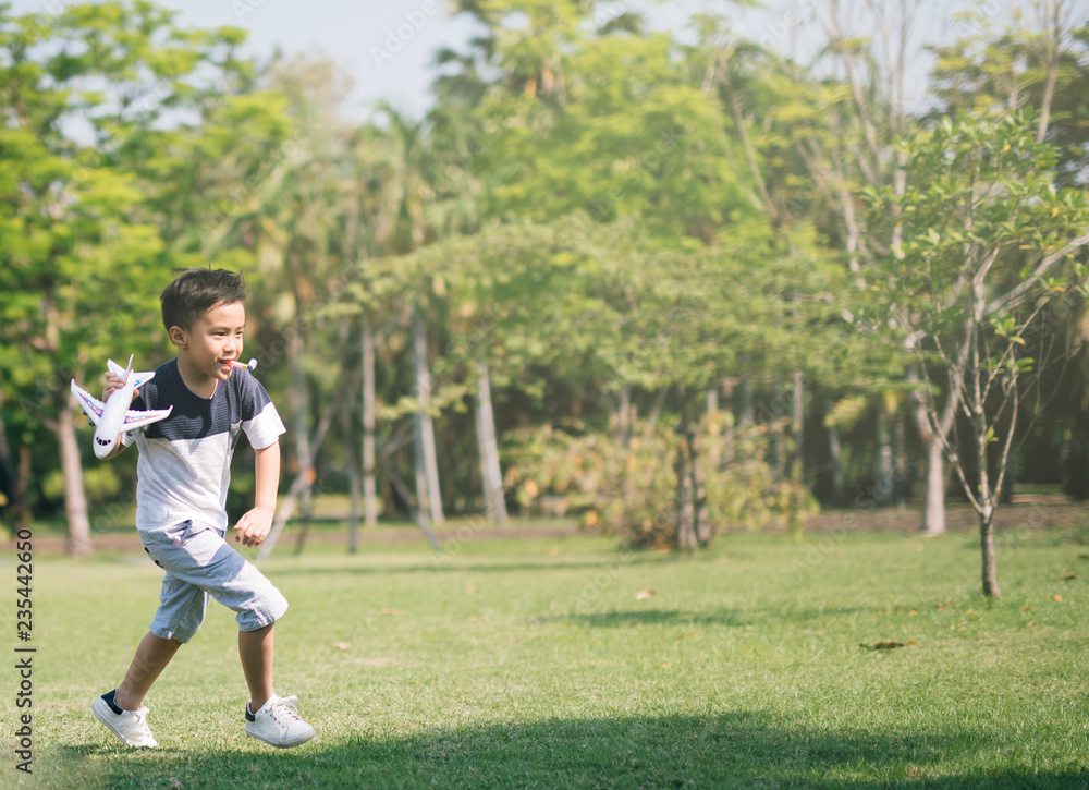 Asian boy playing airplane toy in park outdoors. Asian boy playing airplane toy in park outdoors.