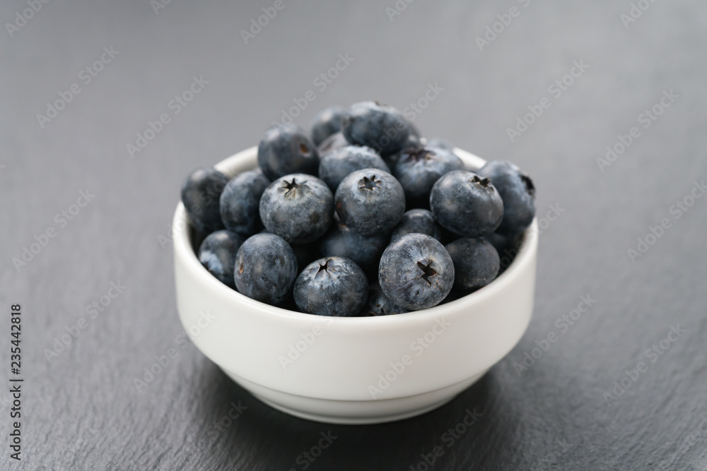 ripe blueberries in white bowl on slate background ripe blueberries in white bowl on slate background