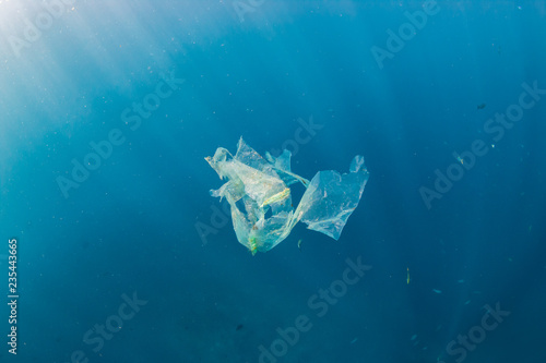 A shredded plastic bag drifting under the surface of a blue, tropical ocean