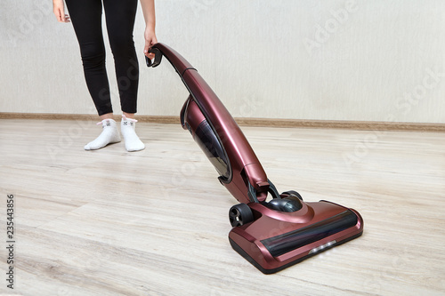 Cleaning woman vacuums with handheld vacuum cleaner with lights on. photo