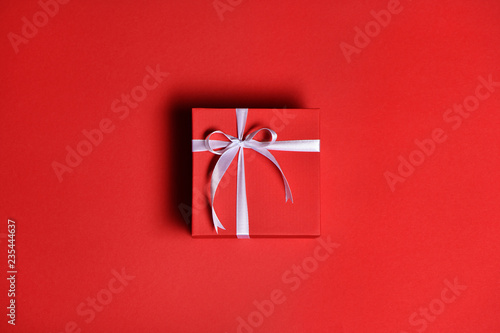 Red gift box with a white bow on red background photo