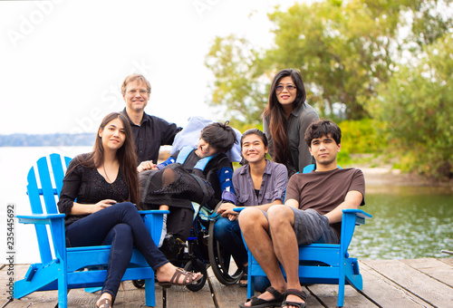 Family with special needs child sitting outdoors together in summer