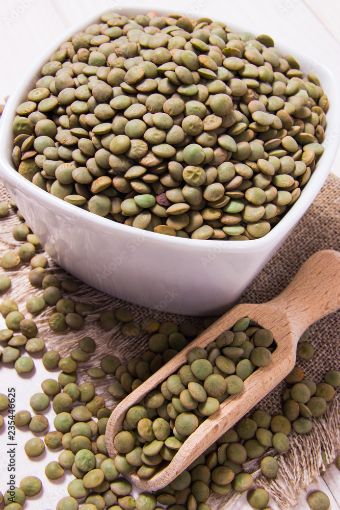 Green lentils in a bowl on a wooden background. Green lentils in a bowl on a wooden background.