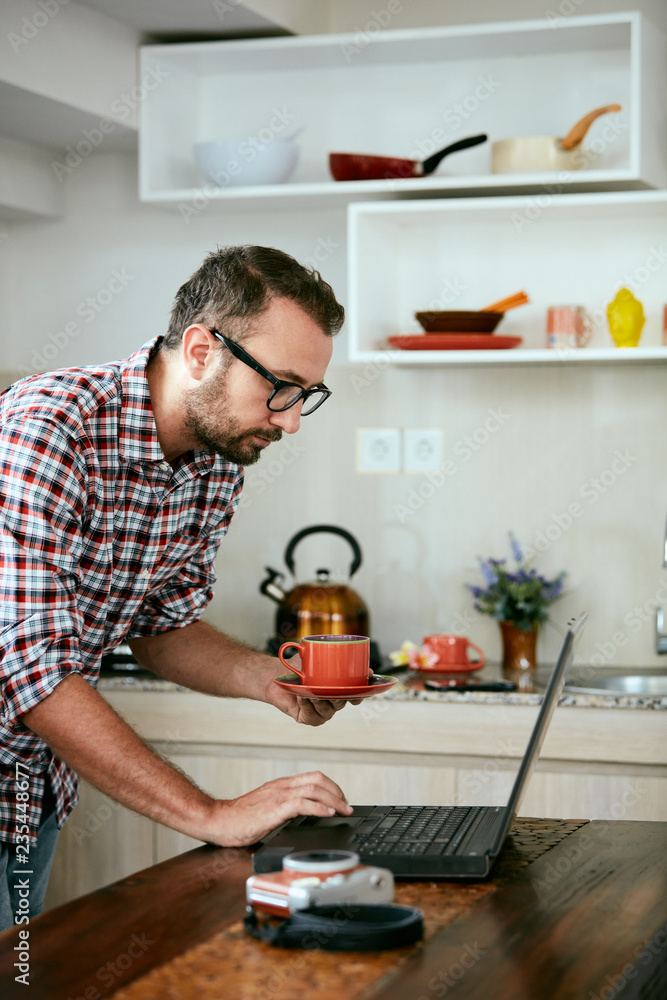Modern bearded man using cellphone and drinking coffee with laptop. Modern bearded man using cellphone and drinking coffee with laptop.
