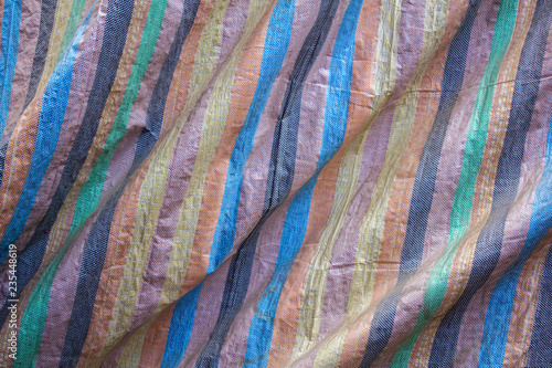collored stripes on the rough fabric with folds. rough surface texture. blue brown black yellow green and pink stripes on the rough fabric with folds. rough surface texture. colored fabric