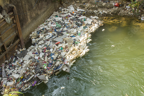 Canvas Print various plastic and rubber garbage on the dam in the river