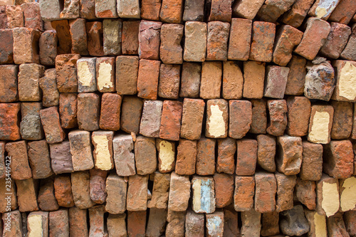 a pile of old red bricks stacked in even rows. rough surface texture