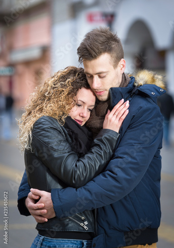 young couple embrace on street in winter