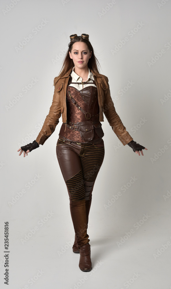 full length portrait of brunette girl wearing brown leather steampunk outfit.  standing pose, on grey studio background. Stock Photo | Adobe Stock