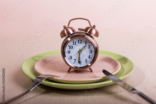 alarm clock on a plate with a fork and knife. chronophagus. timeless symbol. concept