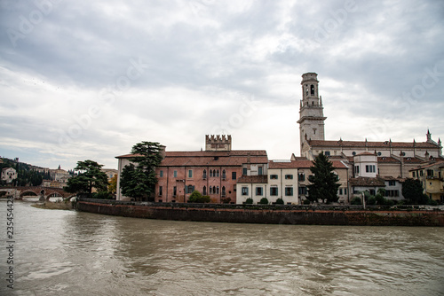 Group of old houses along the Adige river in Verona, Italy. In the picture we can recognize: the bell tower of the cathedral, the cathedral, the archbishopric, the embankments of the river embankment.