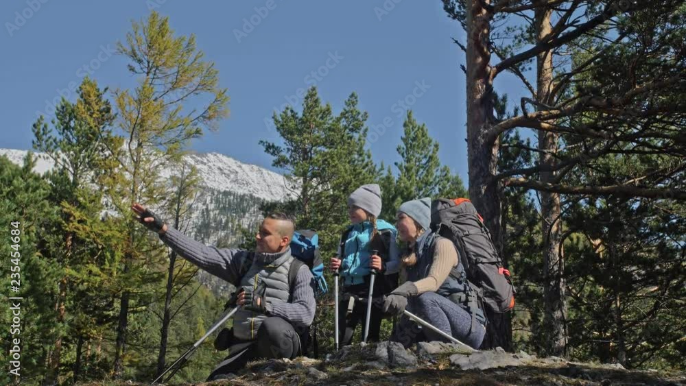 Family travels. People environment by mountains, rivers, streams. Parents and kids walk using trekking poles. Man and woman have professional hiking backpacks, flasks, mugs and other equipment. Dad Family travels. People environment by mountains, rivers, streams. Parents and kids walk using trekking poles. Man and woman have professional hiking backpacks, flasks, mugs and other equipment. Dad