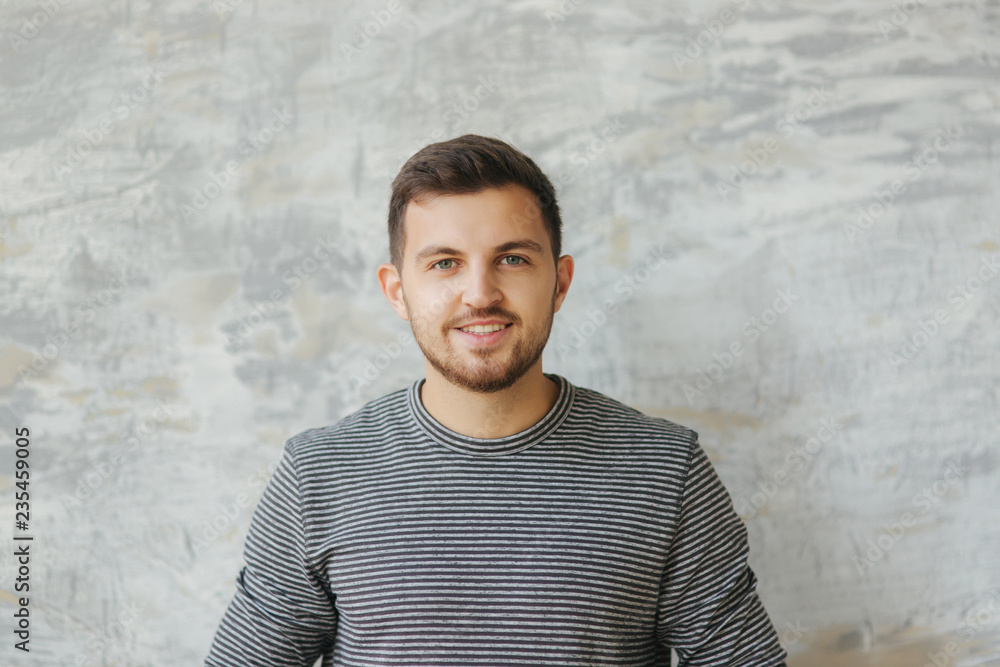 Handsome man with beard stand on the gray background in studio. He smile to camera Handsome man with beard stand on the gray background in studio. He smile to camera