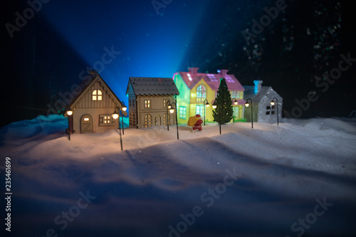 Little decorative houses, beautiful festive still life, cute small houses at night, Night city real bokeh background, happy winter holidays. Selective focus