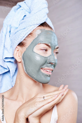 Woman applying mask moisturizing skin cream on face looking in bathroom mirror. Girl taking care of her complexion layering moisturizer. Skincare spa treatment.