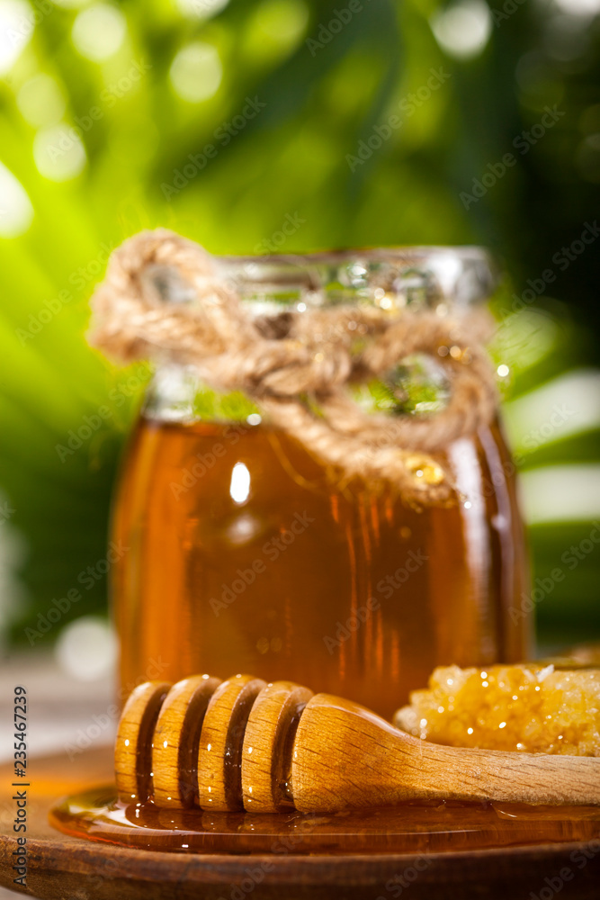 Glass jar of honey with wooden drizzler and chamomile Glass jar of honey with wooden drizzler and chamomile