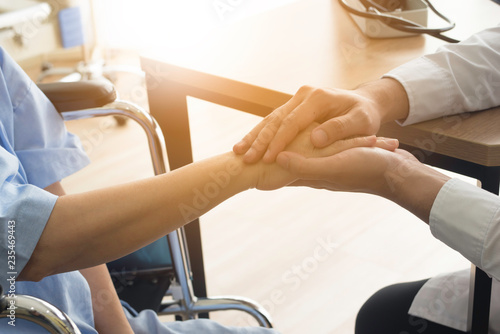 doctor giving encouragement to elderly patient by holding her hands