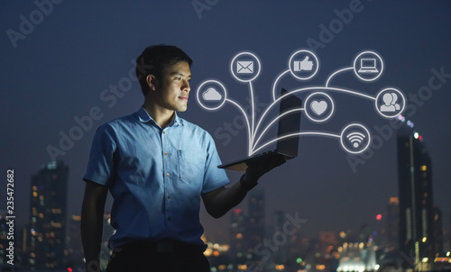 Businessman stand on roof top using laptop with IOT, internet of things,smart city and network connect concept