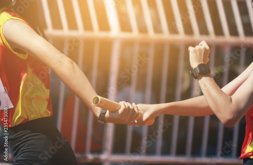 Εκτύπωση καμβά Professional Athlete passing a baton to the partner against race on racetrack