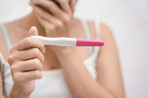 Young asian woman holding pregnancy test and shocked with result in her bathroom, wellness and healthy concept, infertility problem, Selective focus.
