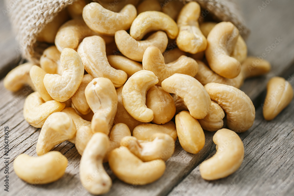 Cashew nuts in burlap bag on wooden gray background . Healthy food Cashew nuts in burlap bag on wooden gray background . Healthy food