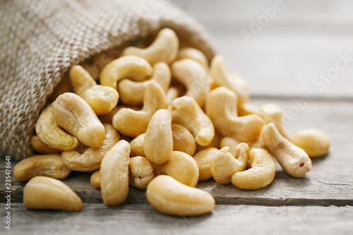 Cashew nuts in burlap bag on wooden gray background . Healthy food