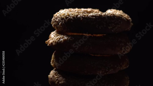 Fresh bagels with sesame seeds in rotation. Black background. Extreme closeup.