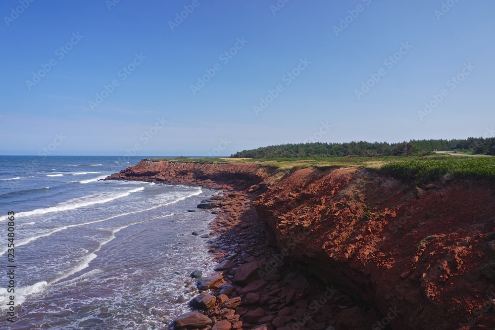 Obraz premium Prince Edward Island, Canada: A red sandstone beach under a clear blue sky on the north shore of Prince Edward Island, in the Gulf of St. Lawrence.