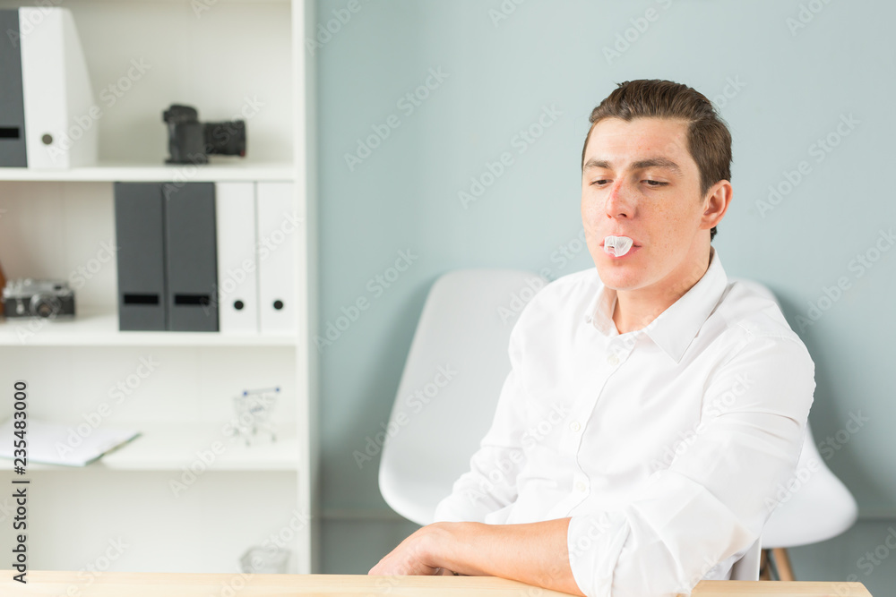 People, fools and fun concept - man in office blowing bubble with gum