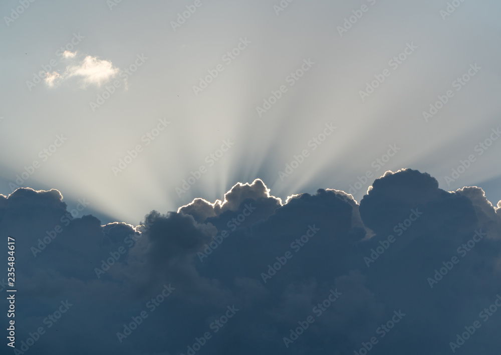 Sun rays from behind clouds on blue sky