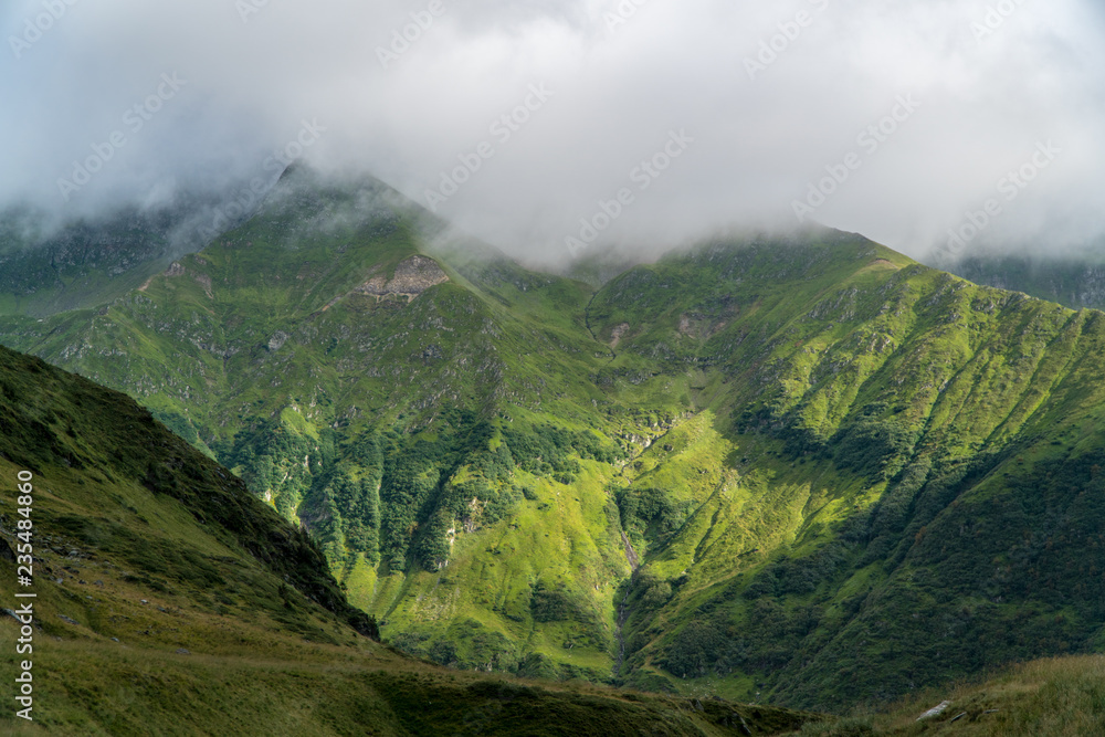 Panoramic view of green mountains peaks covered by clouds