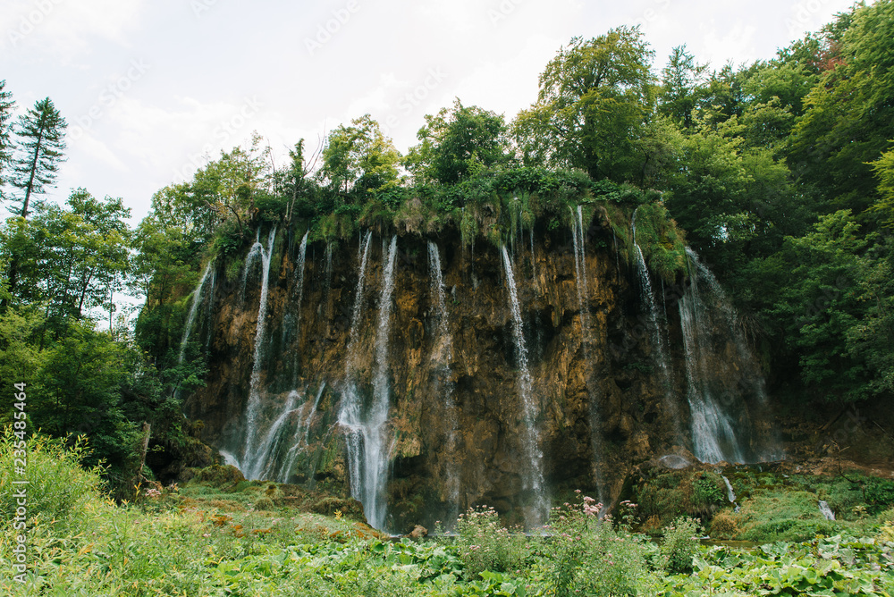 Travel to Croatia. Plitvice Lakes is a popular Croatian national park of incredible beauty. Photo of a favorite point among tourists - a stunning waterfall surrounded by greenery