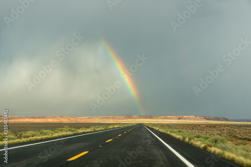 End of a rainbow on a black a road, south west America © Kristian
