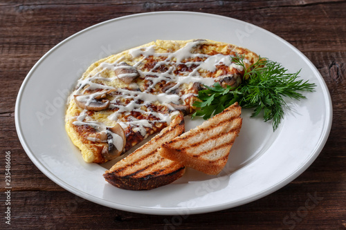 Vegetarian breakfast: scrambled eggs with mushrooms, greens and croutons on a white plate